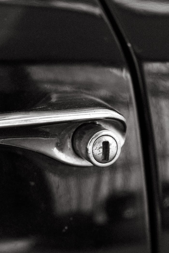 Close-up of a vintage car door handle, captured in monochrome for a timeless feel.