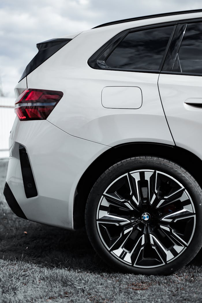 Close-up of a white SUV focusing on the rear wheel and taillight in an outdoor setting.